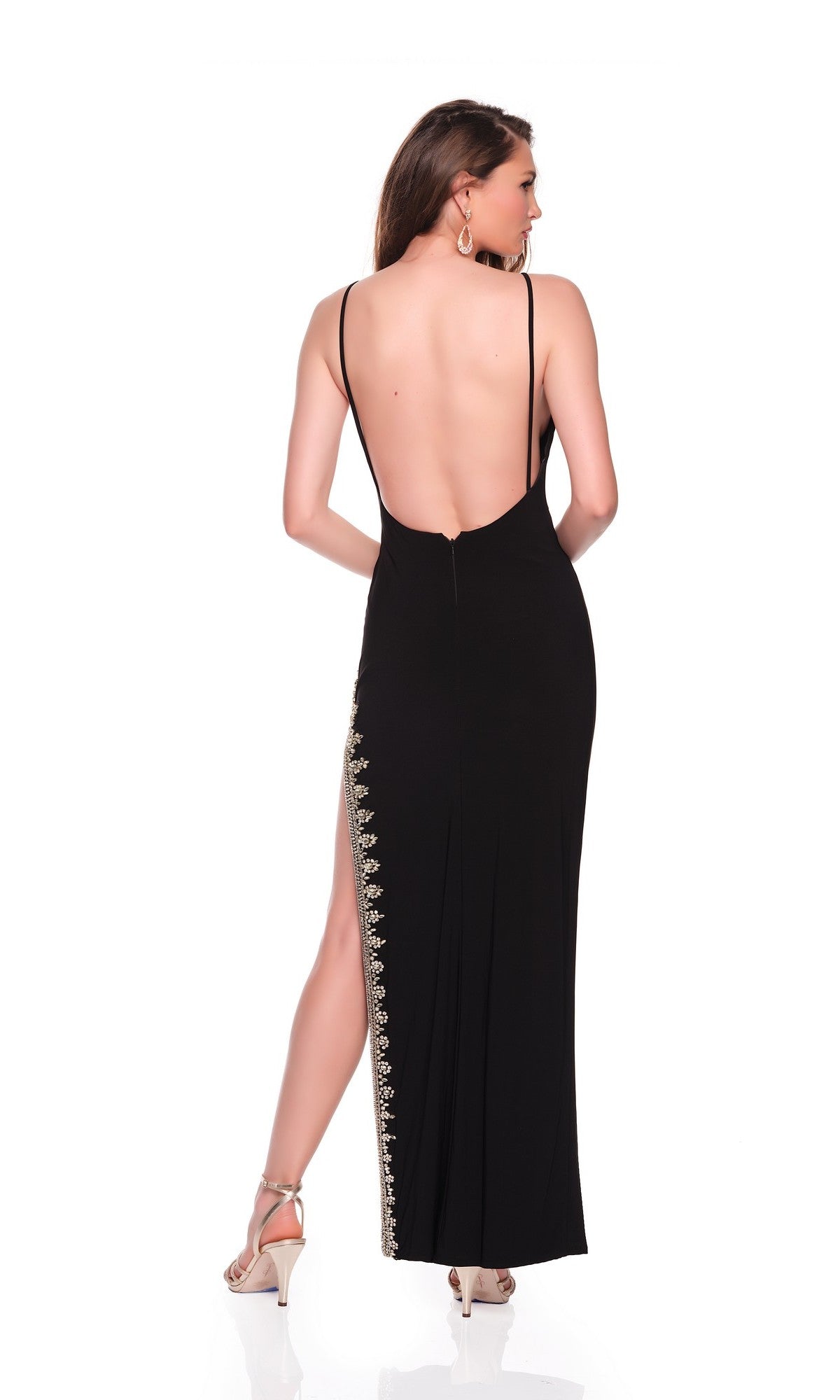 A woman wearing the Dave and Johnny 12819 long black prom dress featuring thin straps, a backless design, and a high-leg slit, stands in high-heeled sandals against a white background.